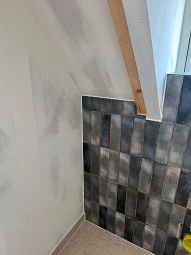 Nieuw kitwerk in een badkamer met schuine wanden en verschillende tegelsoorten